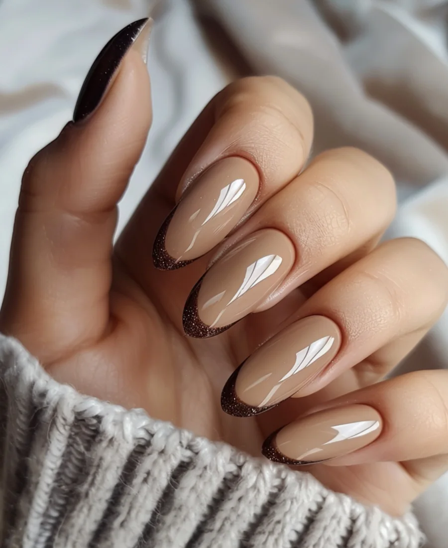 Närbild på beige naglar med mörk detalj